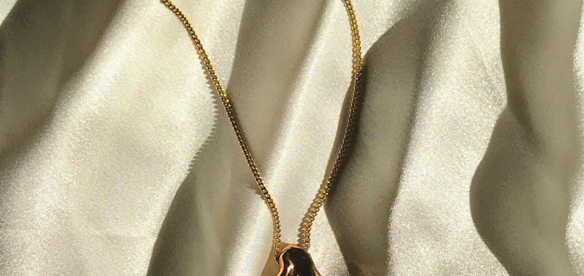 Gold necklace placed on shiny material